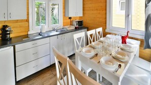 A modern kitchen with white cabinets, a wooden countertop, and a dining area set for four with white chairs and a table set for a meal. - Large Holiday Homes, Swimming Pool, Jacuzzi (Ustronie Morskie)