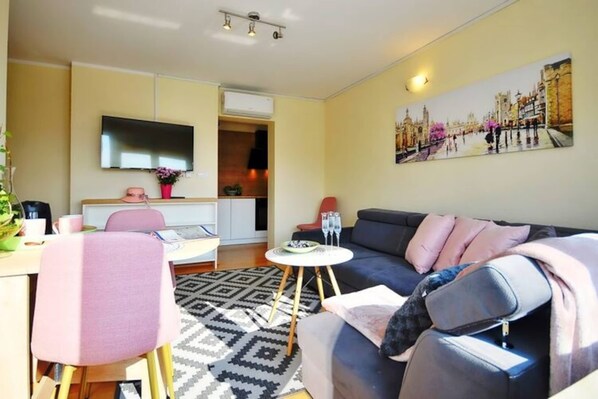A modern living room with a sofa, a dining table, and a TV. - Comfortable Holiday Apartment Close to the Beach (Ustronie Morskie)