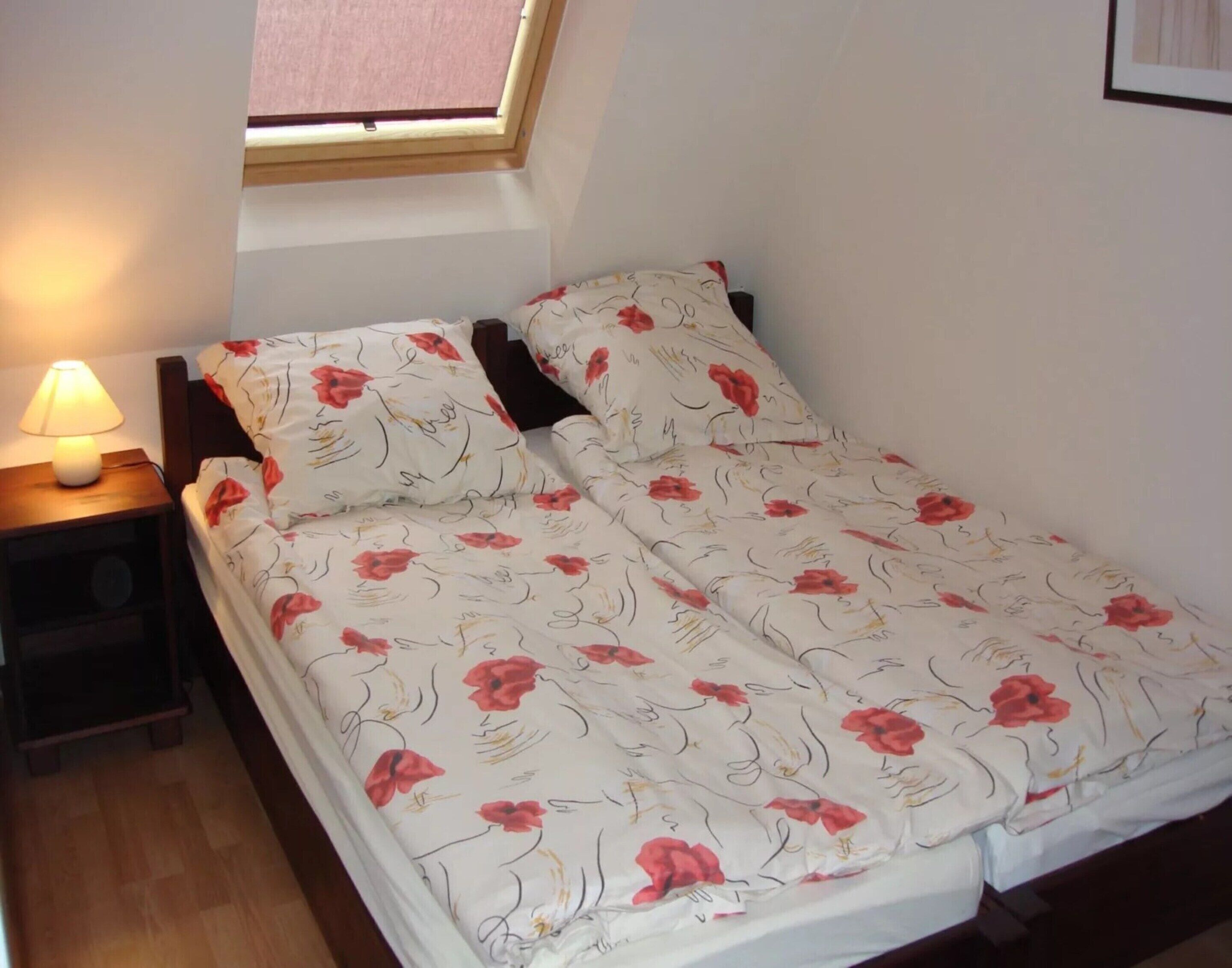 Un dormitorio con una cama, una mesita de noche con lámpara y una ventana con vistas.