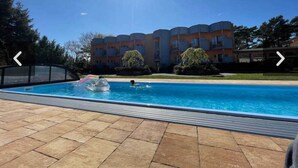 A swimming pool with a tiled deck, surrounded by a multi-story building with balconies. - House for 6 With Swimming Pool (Trzebiatow)