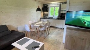 A cozy living room with a sofa, a dining table with chairs, a TV, and a kitchen area with a window. - House for 6 With Swimming Pool (Trzebiatow)
