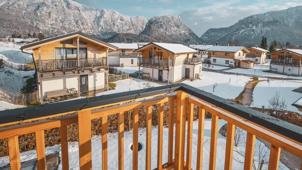 Un pueblo en la montaña cubierto de nieve, con casas de madera y barandilla de balcón de madera.