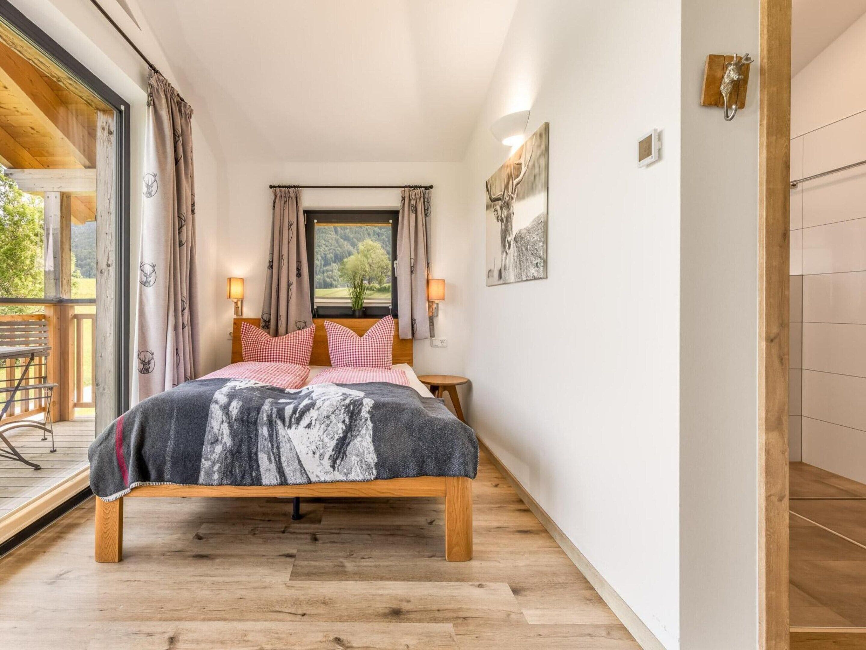 A bedroom with a wooden bed, two bedside lamps, a window with curtains, and a view of the outdoors.