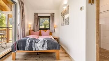 Un dormitorio con cama de madera, dos lámparas de noche, una ventana con cortinas y vistas al exterior.
