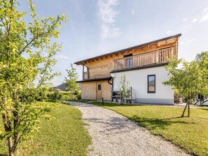 A two-story wooden house with a balcony, surrounded by a well-maintained lawn and a gravel path. - Chalet Alpenzauber mit Beheiztem Pool, Inzell (Inzell)