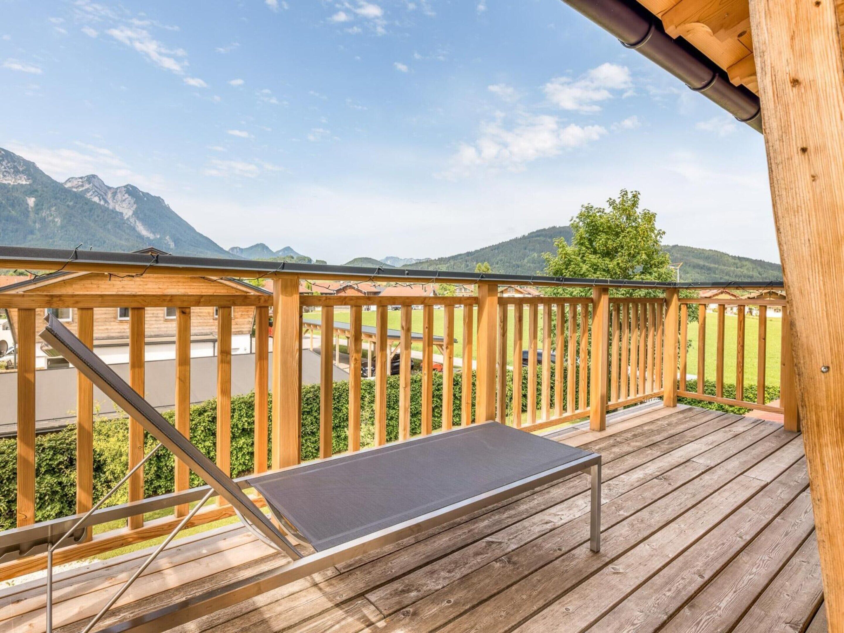 Um deck de madeira com um banco de metal, com vista para uma paisagem montanhosa.