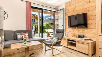 A modern living room with a sofa, a chair, a coffee table, a TV, and a wooden wall.