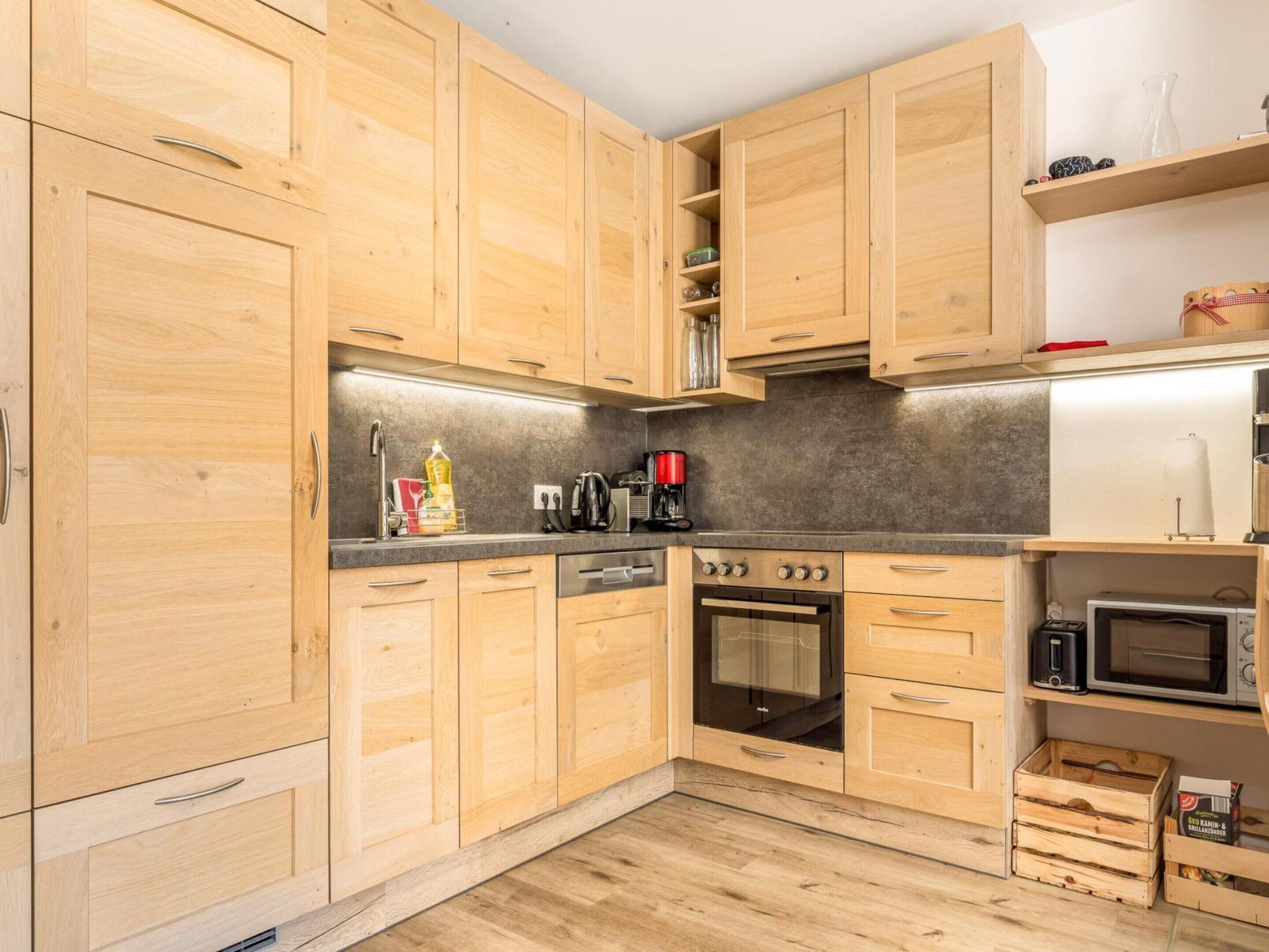 A kitchen with wooden cabinets, a built-in oven, a microwave, and a coffee maker.