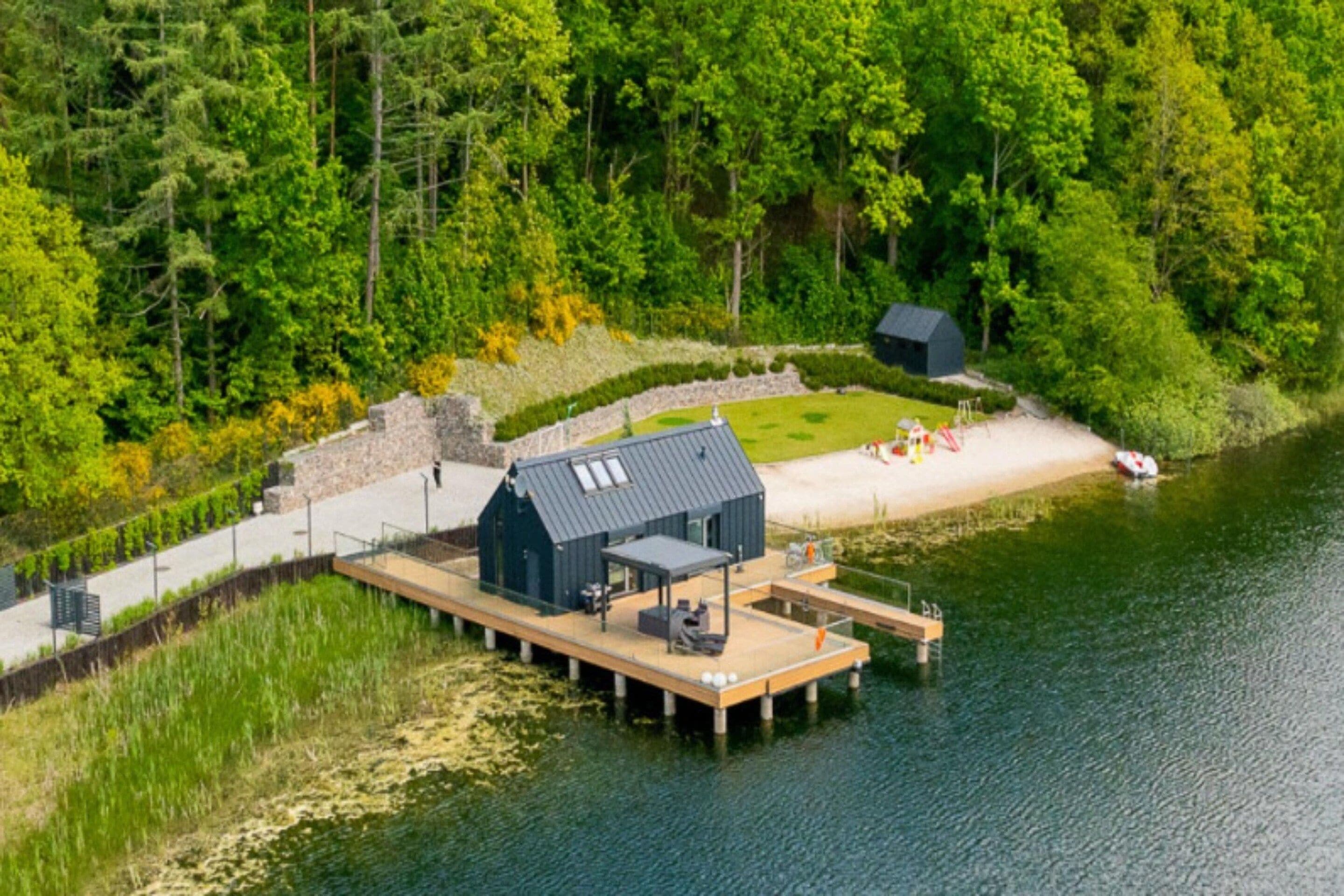 A lakeside cabin with a dock, surrounded by dense forest.