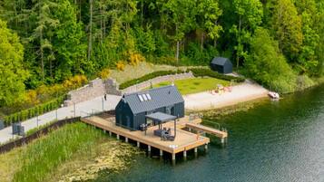 A lakeside cabin with a dock, surrounded by dense forest.
