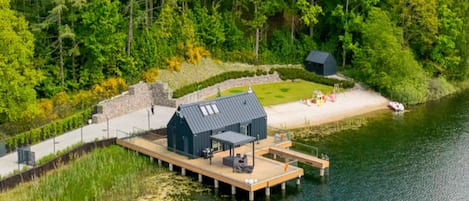 A lakeside cabin with a dock, surrounded by dense forest.