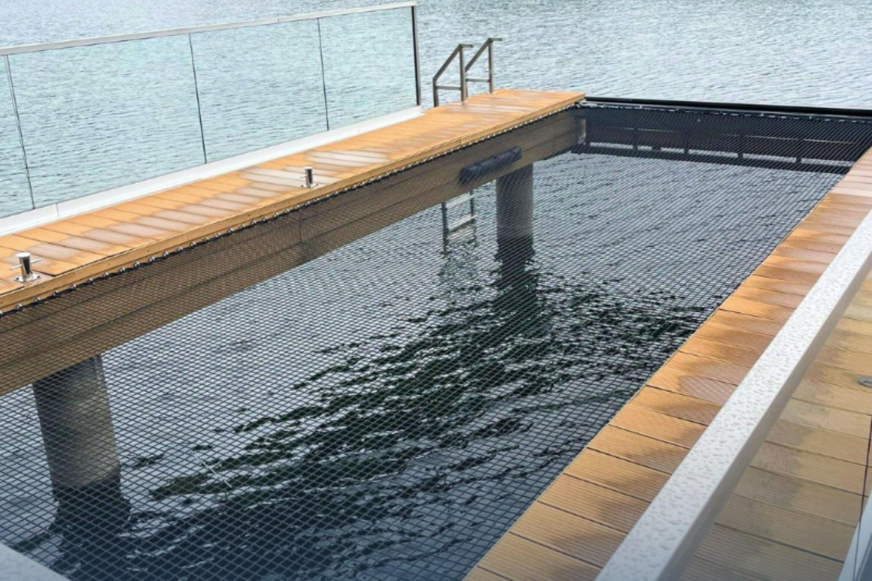 A pool with a wooden deck and a metal safety railing.