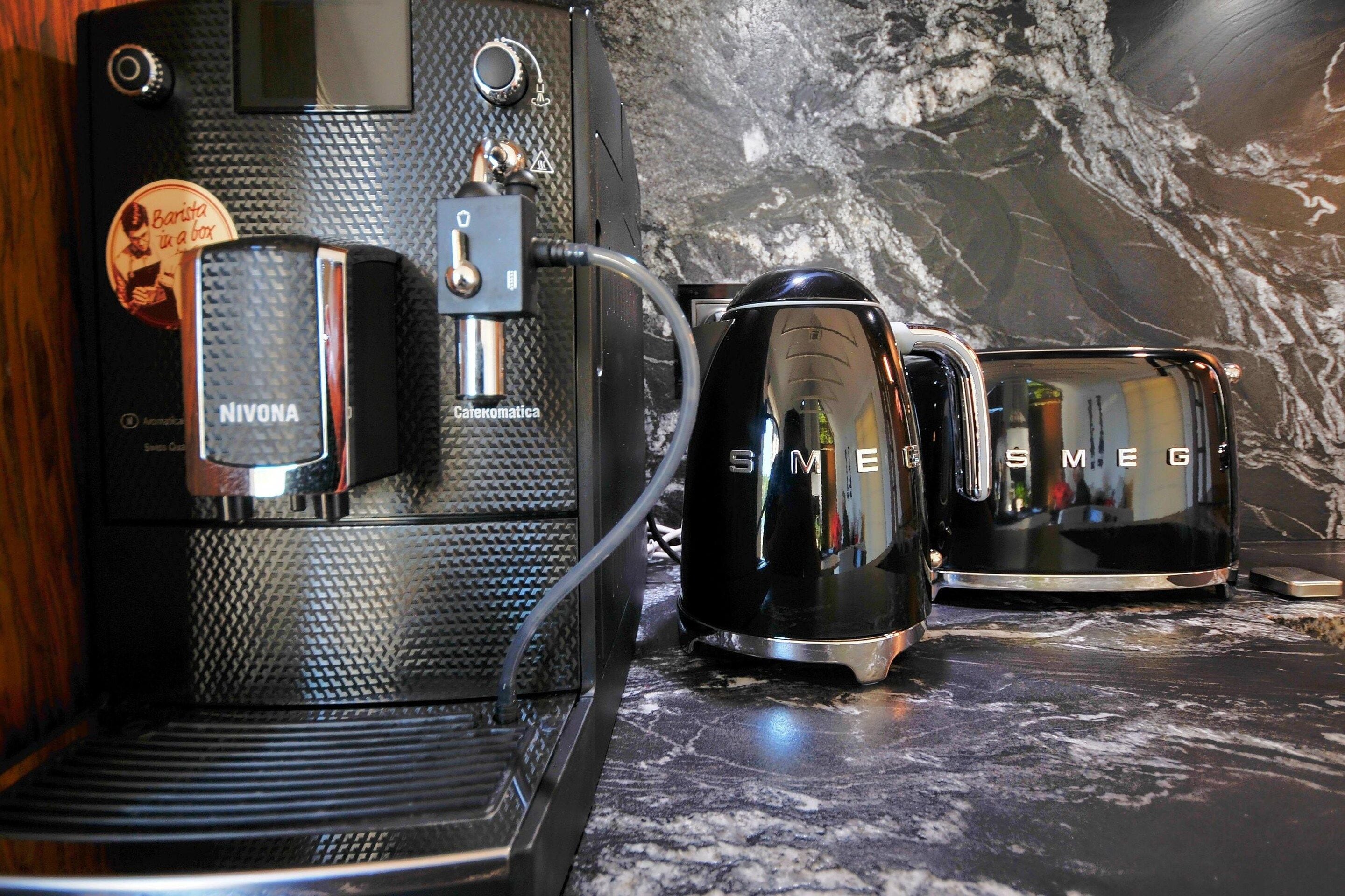 Une machine à café dotée d’un distributeur de capsules de café de marque, reliée à une chaudière et à une cafetière.