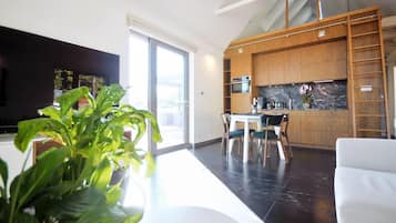 A modern kitchen with wooden cabinets, a built-in oven, and a dining area with a table and chairs.