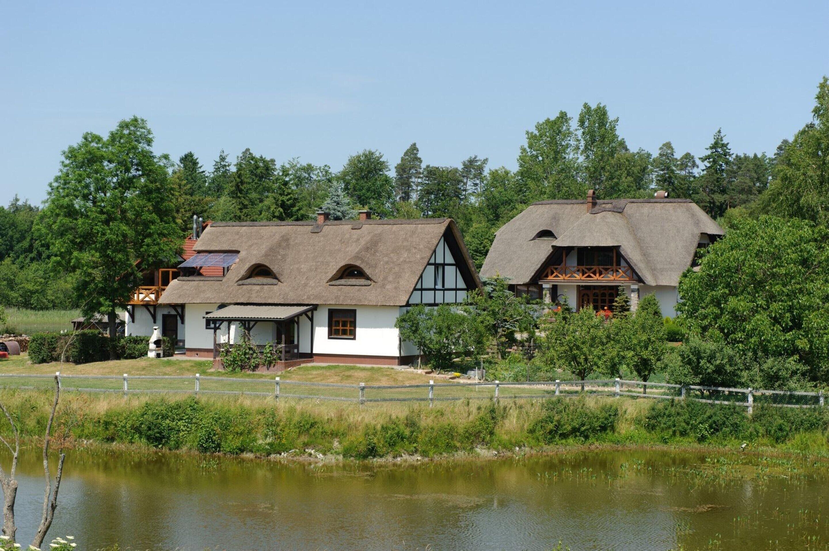 A traditional house with a thatched roof, white walls, and a wooden porch.