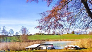 A lakeside picnic area with benches and picnic tables, surrounded by trees and a grassy field. - Holiday Home With Thatched Roof, Rekowo (Bytow)