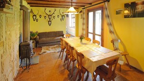 A dining area with a wooden table and chairs, a sofa, and a ceiling with wooden beams. - Holiday Home With Thatched Roof, Rekowo (Bytow)