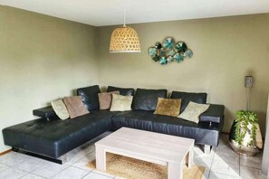 A living room with a sectional sofa, a coffee table, a hanging light fixture, and decorative wall art.