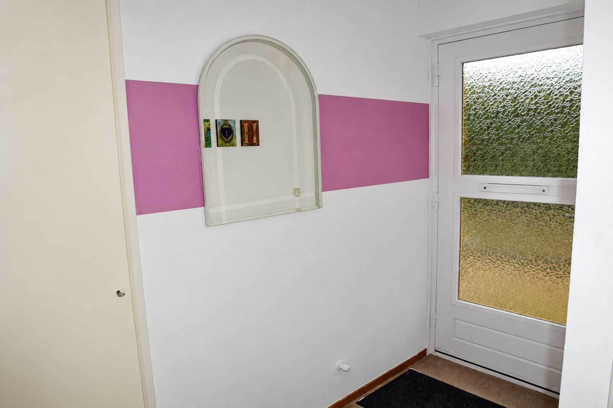 Ein Flur mit einer weißen Tür, einer Glastür mit Sandstrahlmuster und einer Wand in Rosa.