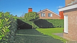 A residential property with a well-maintained lawn, a brick house, and a chimney. - House in Breskens near the Beach (Breskens)