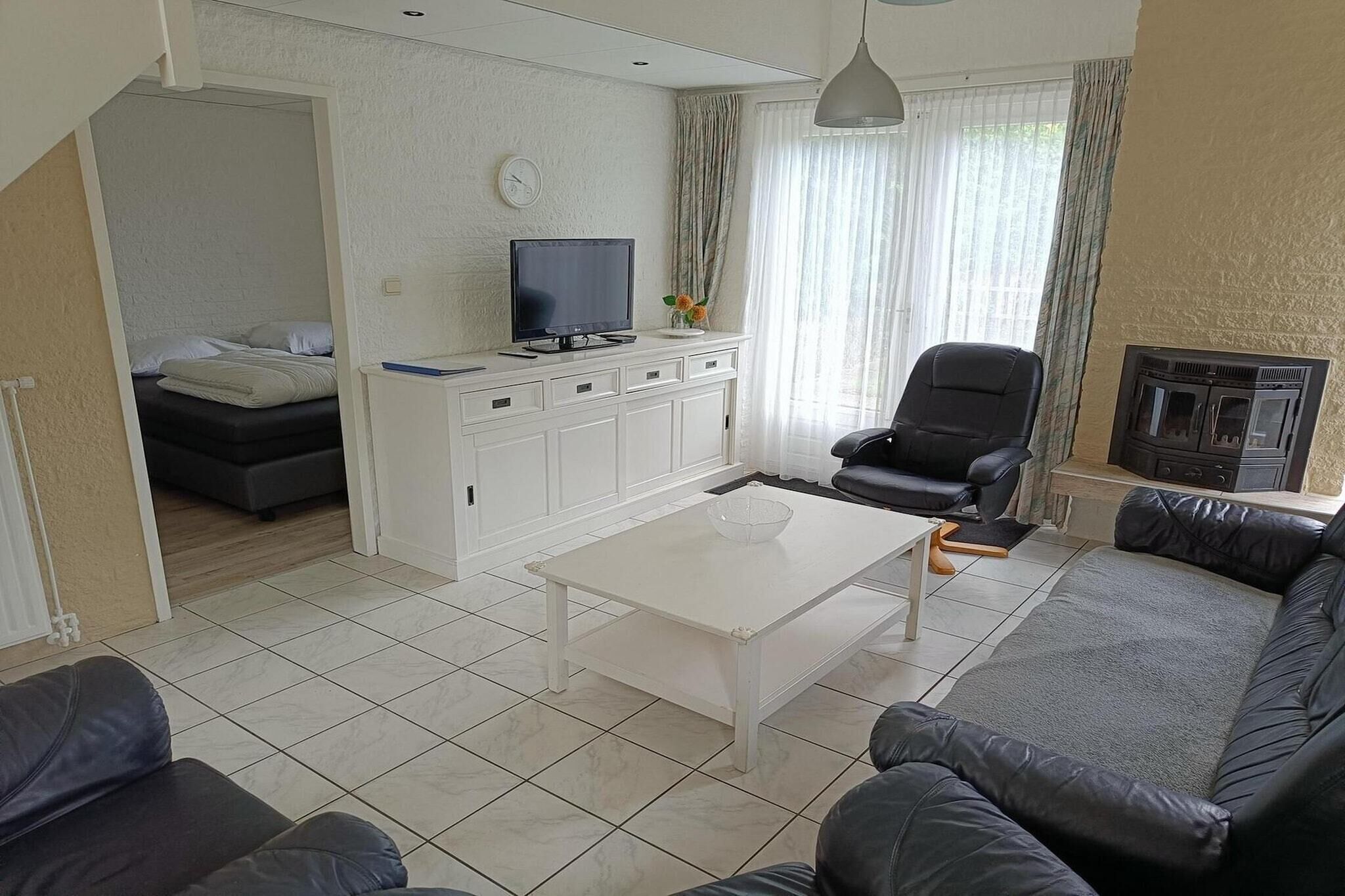 Un salon avec un canapé, un téléviseur posé sur un meuble, une table basse et une cheminée.