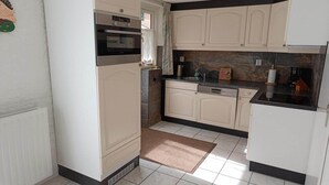 A kitchen with white cabinets, a built-in oven, a dishwasher, and a granite countertop.