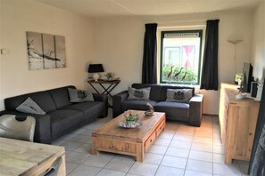 A living room with two sofas, a coffee table, a lamp, and a window with curtains.