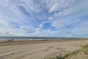 Uma praia extensa com céu claro e mar tranquilo.