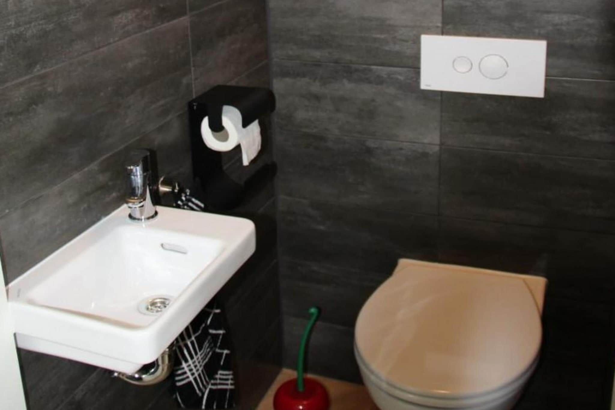Un baño con un lavamanos blanco, un inodoro y un cubo de basura negro.