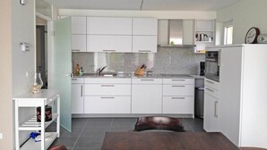 A modern kitchen with white cabinets, a granite countertop, and a built-in oven.