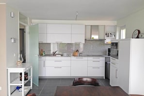A modern kitchen with white cabinets, a granite countertop, and a built-in oven.