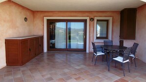 A patio with a table and chairs, a sliding glass door, and a wooden cabinet. - Apartment for 6 People, Cannigione (Arzachena)