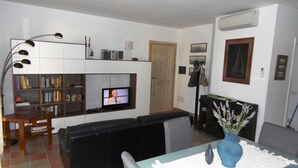 A living room with a TV, sofa, and a dining area with a table and chairs. - Apartment for 6 People, Cannigione (Arzachena)