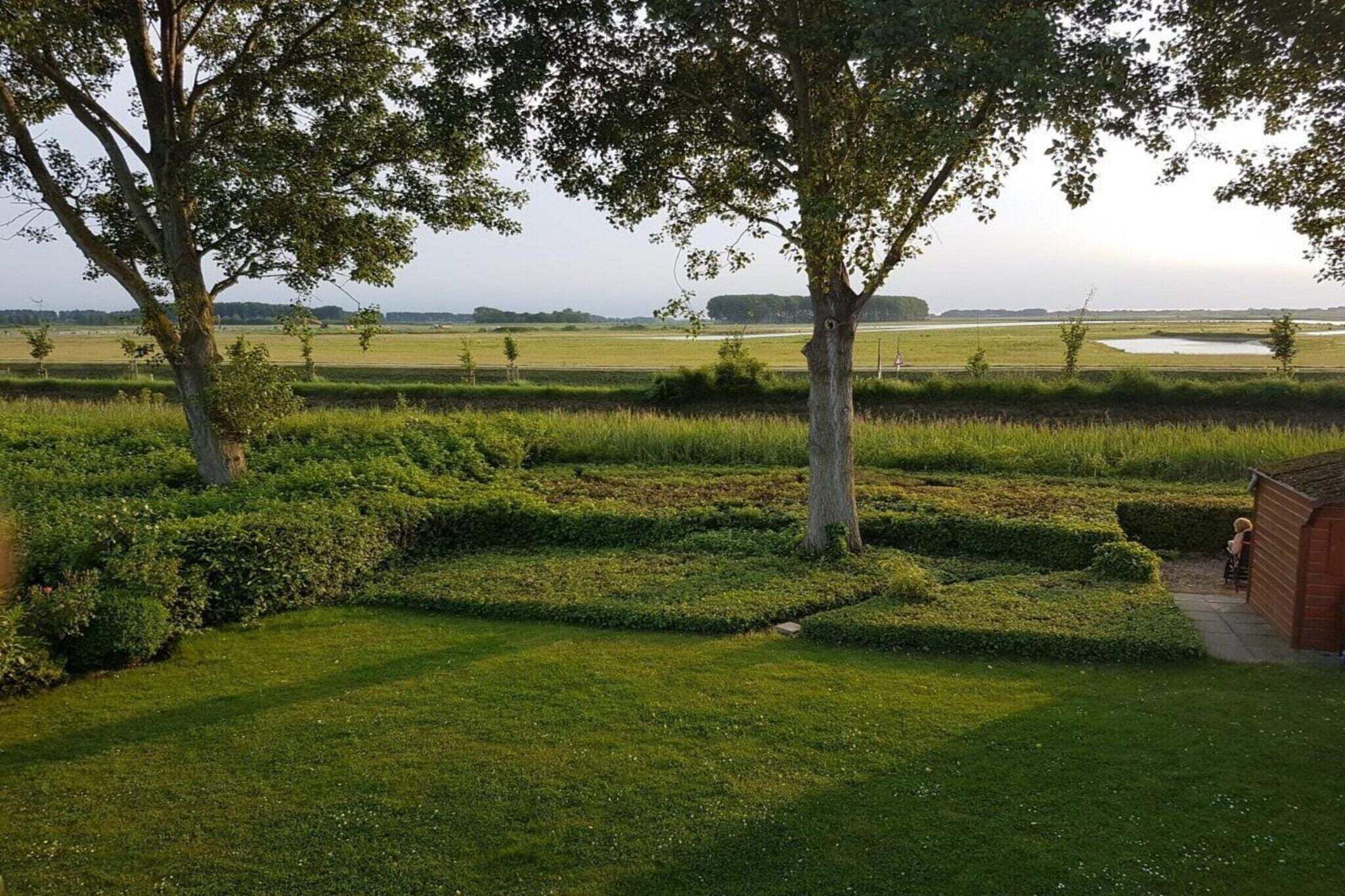Ein angelegter Garten mit Bäumen, Hecken und einem Gebäude.