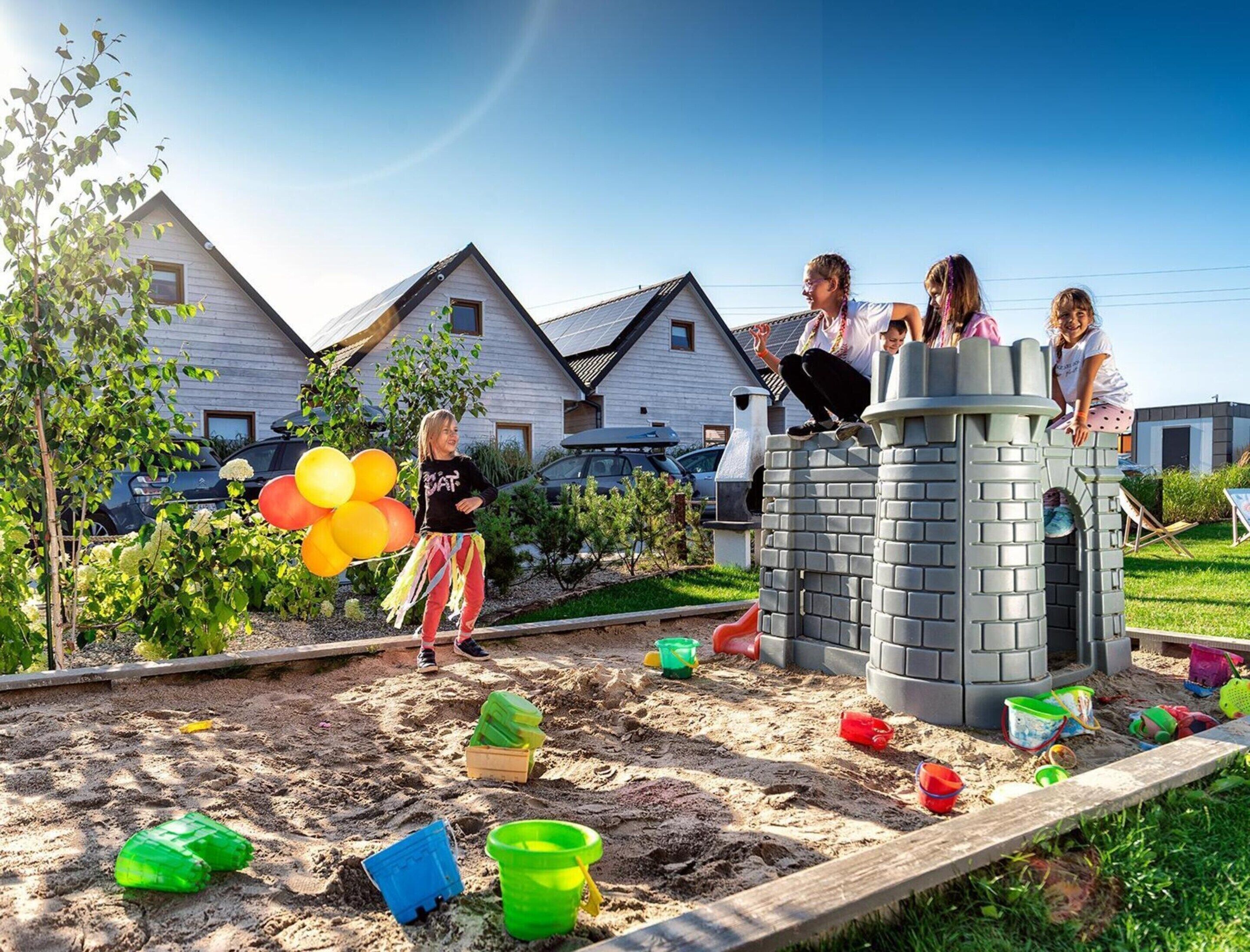 A sandy play area with a castle-like structure, surrounded by houses.