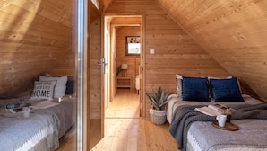 A cozy attic bedroom with wooden walls, a central door leading to a hallway, and a small window. - Holiday Homes With Pool, Attractions for Children (Mielno)