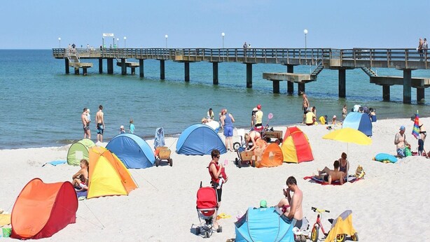 A beach with multiple colorful tents and a pier in the background. - Ferienhaus, Boiensdorf (Boiensdorf)