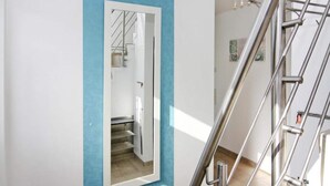 A modern interior with a blue accent wall, a metal staircase, and a mirror reflecting a staircase. - Ferienhaus, Boiensdorf (Boiensdorf)