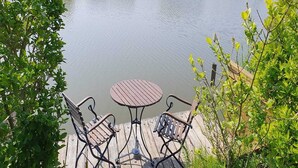 A wooden deck with a round table and two chairs, overlooking a calm body of water. - Eco-Friendly Holiday Home (Breskens)