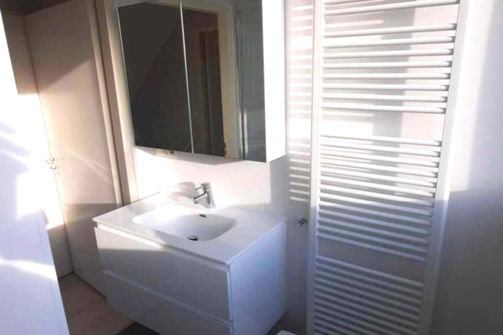 A bathroom with a white sink, mirror, and a white cabinet.