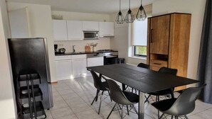 A modern kitchen with white cabinets, a black dining table, and chairs.