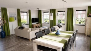 A modern living room with a sofa, dining table, and TV.