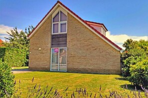 A single-story building with a pitched roof, a large window, and a metal gate. - Bungalow in Breskens near Waterfront Beach (Breskens)