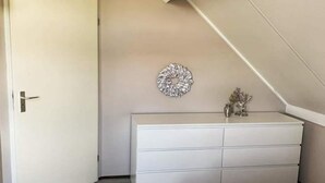 Ein Schlafzimmer mit einem weißen Schminktisch, einer Wanddekoration und einer Tür.