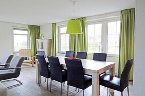 Uma sala de conferências com uma mesa comprida, algumas cadeiras e uma luminária pendente verde vibrante.