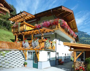 Una cabaña con balcones de madera, jardineras con flores y un muro de piedra.