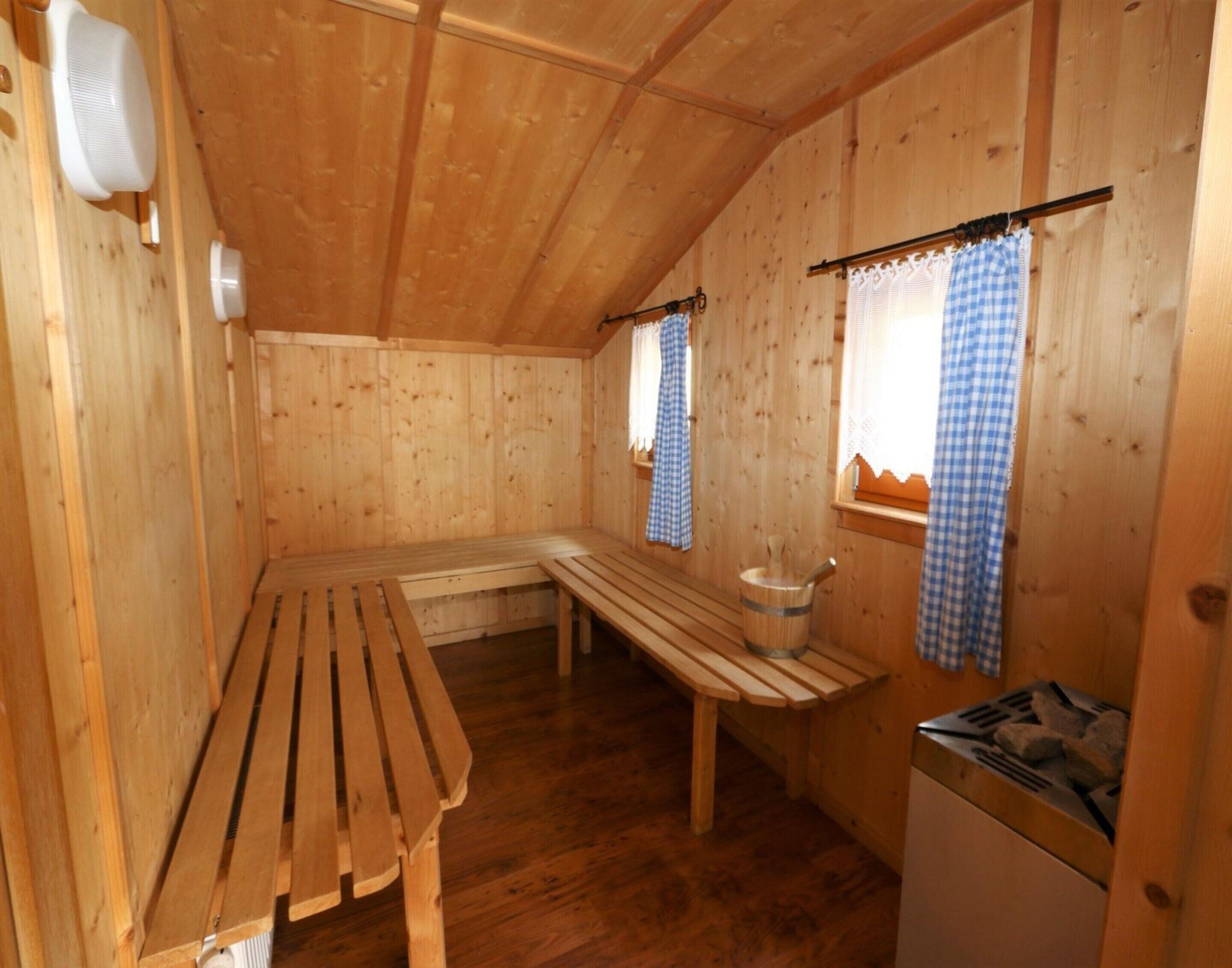Una cabaña de madera con un banco, una mesa y una estufa.