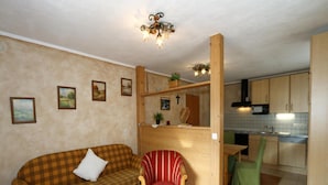 A compact living space with a sofa, armchair, and a small table. A kitchen area is visible with cabinets and a microwave. - Chalet in Grossarltal With Panoramic Views (Grossarl)