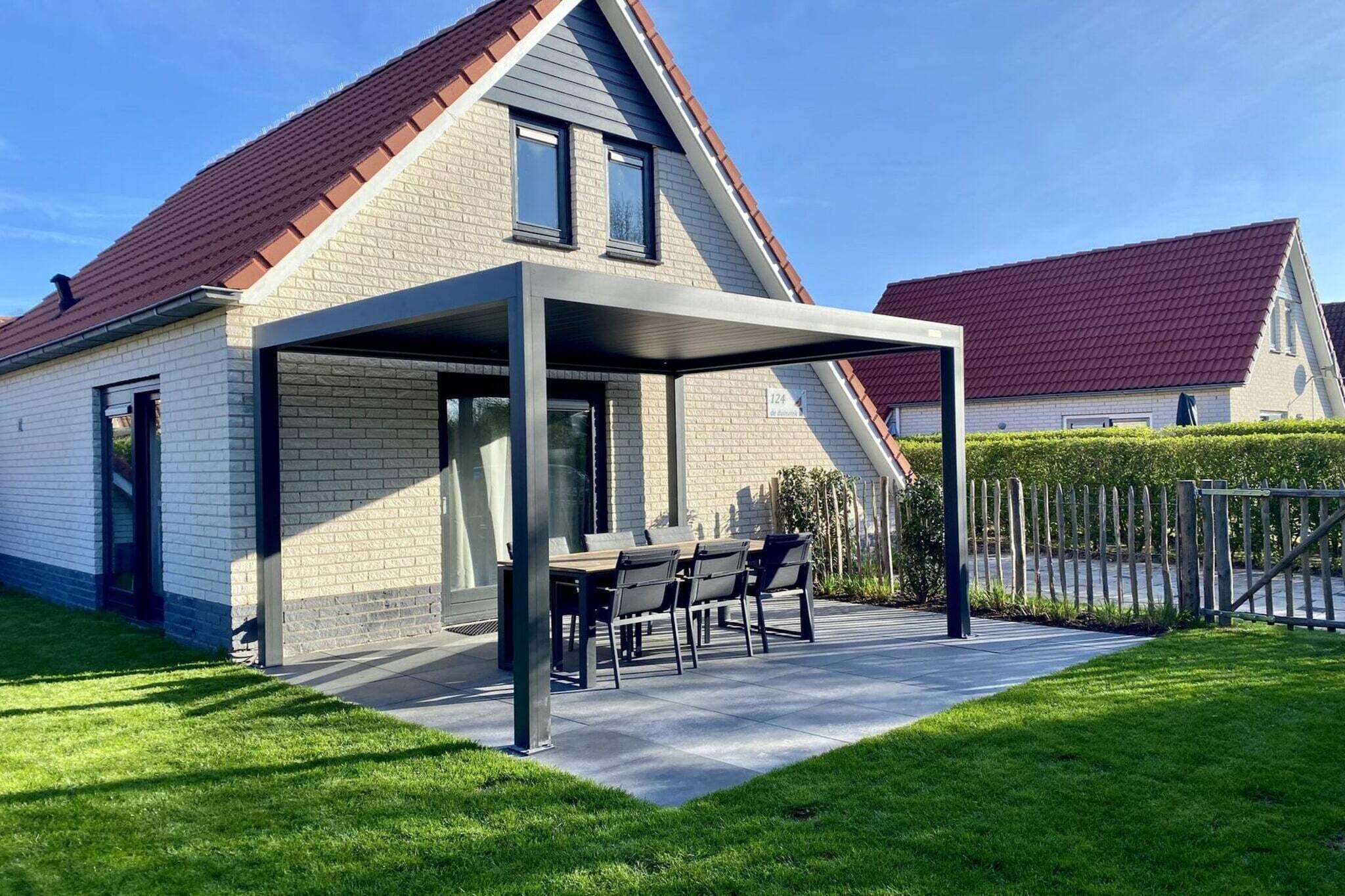 Ett modernt hus med en täckt uteplats, en fasad av tegel och ett tak täckt med röda tegelpannor.