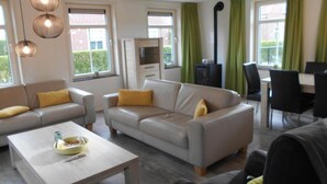 Un salon comprenant un canapé, une table basse, un téléviseur et un coin repas avec des chaises.